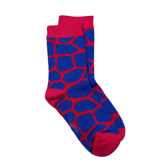 A pair of seamless bamboo crew socks featuring a bold blue and red giraffe-like abstract pattern, with solid red cuffs, toes, and heels, displayed against a plain white background.